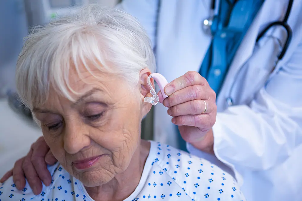 Healthcare provider assisting a senior with a hearing aid fitting
